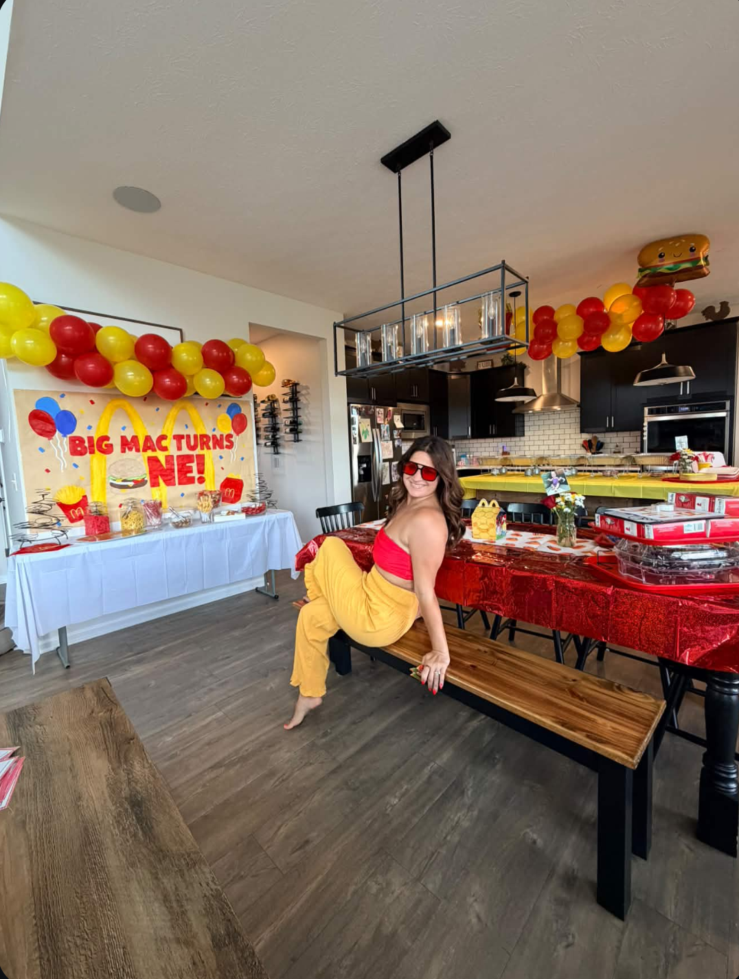 Founder styling a themed first birthday party with balloon garland and red tablescape